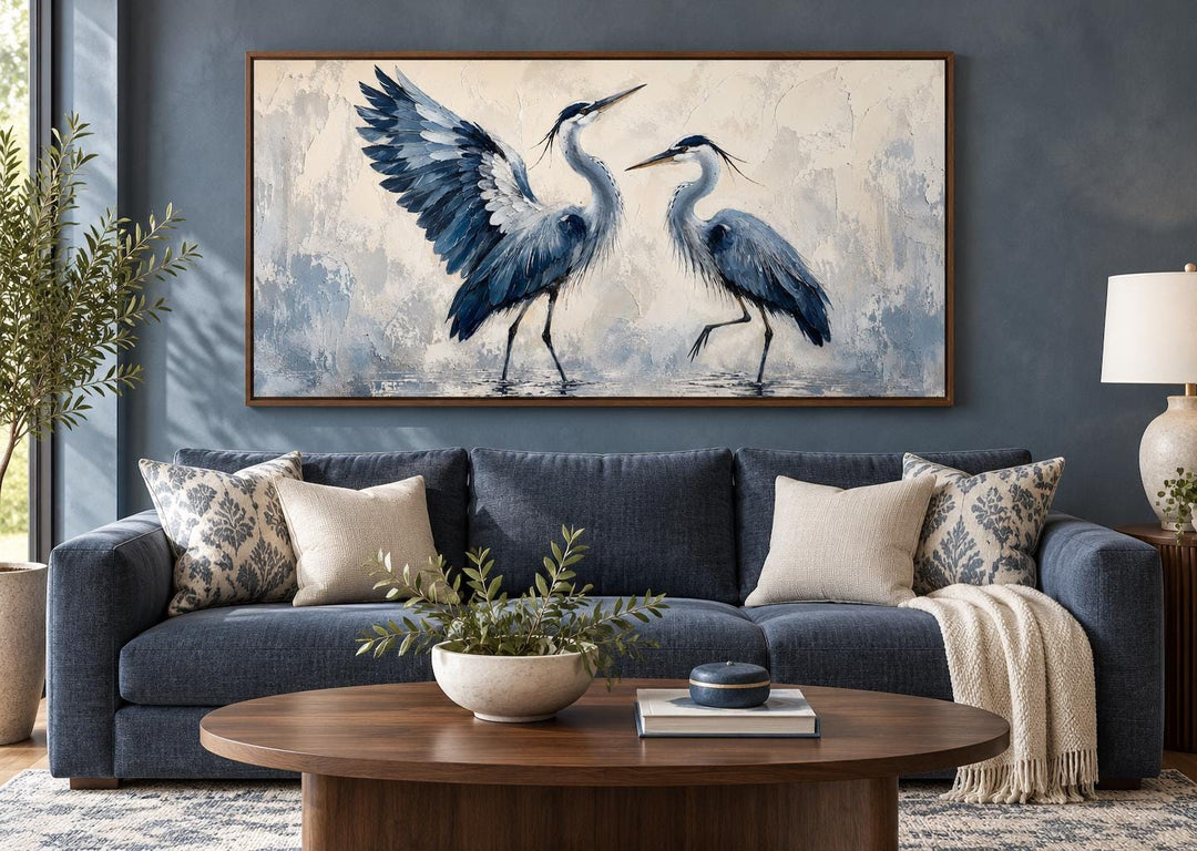 Dancing Blue Herons navy blue and cream canvas wall art above a blue sofa in a living room.
