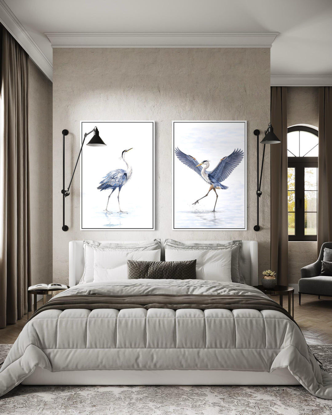 Set of two watercolor heron canvas prints hanging above a bed in a neutral-toned bedroom.