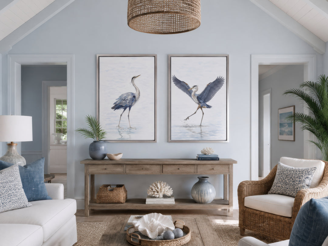 Set of two watercolor heron bird canvas prints in silver frames above a wooden console table.