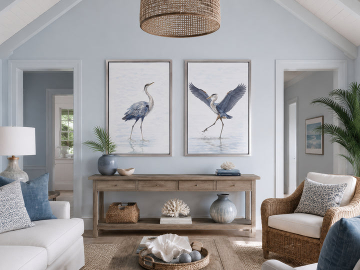 Set of two watercolor heron bird canvas prints in silver frames above a wooden console table.