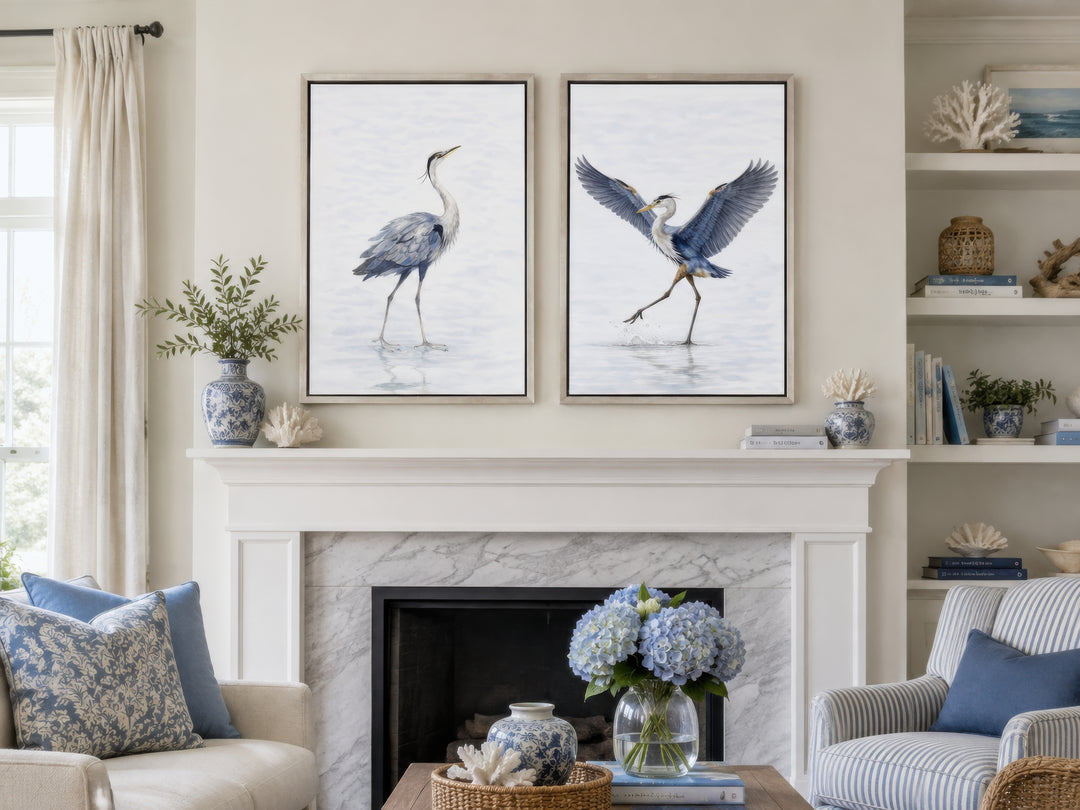 Set of two watercolor heron canvas prints in silver frames hanging above a white fireplace mantel.