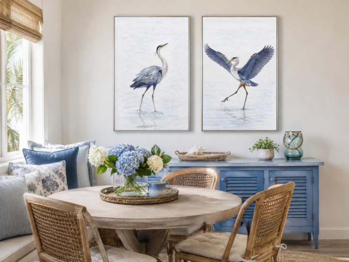 Set of two watercolor heron bird canvas prints in a coastal dining room with blue and white accents.