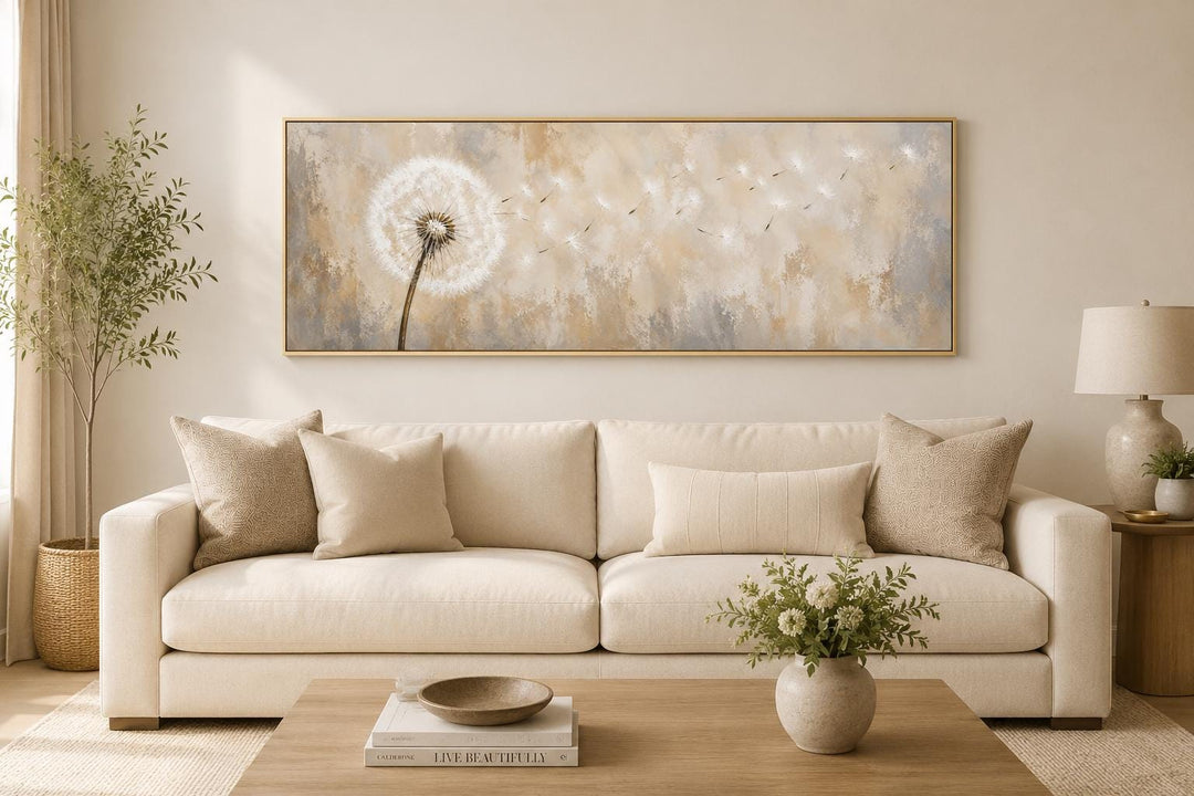 Long horizontal dandelion seeds wall art in neutral tones hanging above a beige sofa.