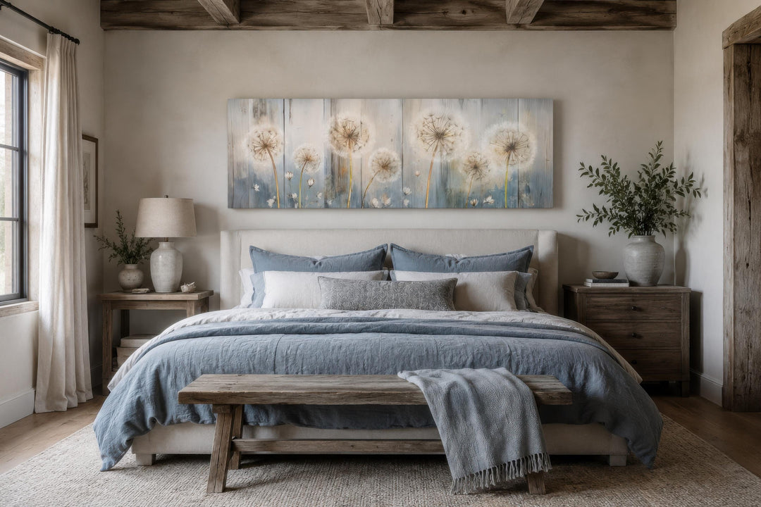 Long horizontal canvas with dandelion floral print in blue and cream above a farmhouse bed.