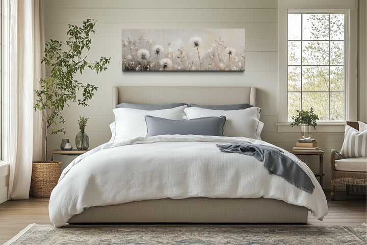 Long horizontal wall art of white dandelions in a neutral field above a bed in a farmhouse bedroom.