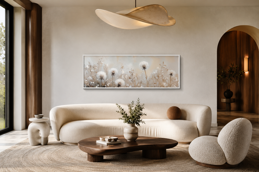 Long horizontal wall art of white dandelions in neutral beige tones above a modern curved sofa.