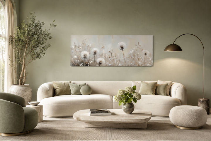 Long horizontal wall art of white dandelions in a neutral farmhouse living room above a sofa.