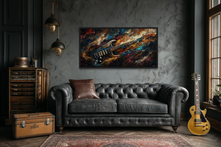 Framed canvas wall art of a colorful abstract electric guitar above a black leather sofa.