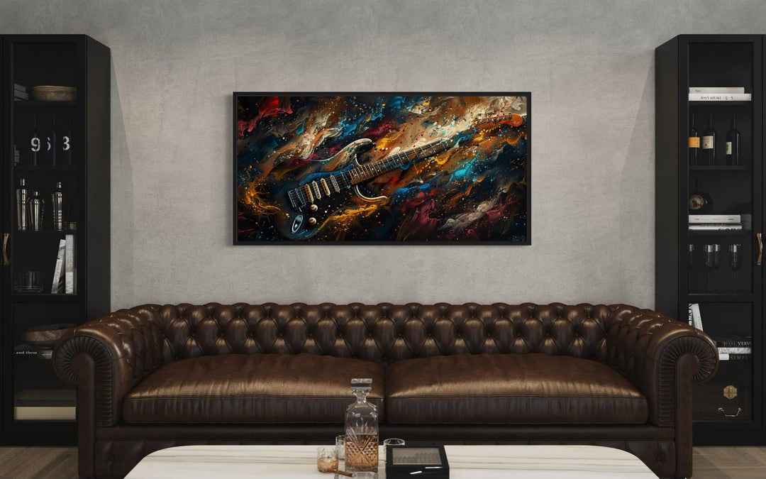 Dark colorful electric guitar framed canvas wall art above a brown leather sofa in a music room.