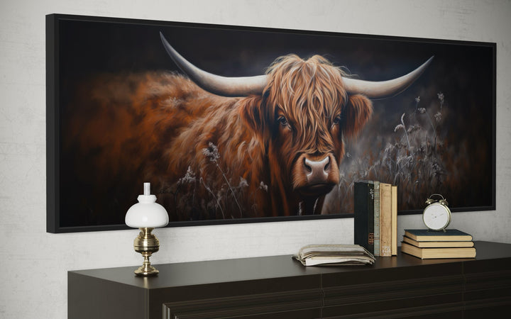 Long horizontal canvas wall art of a dark Highland cow with large horns above a dark wood dresser.