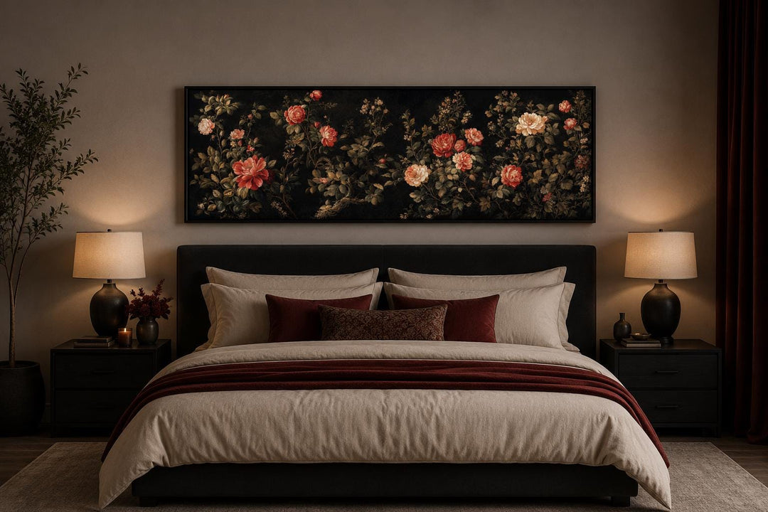 Dark moody floral canvas print with red and cream roses in a long horizontal frame above a bed.
