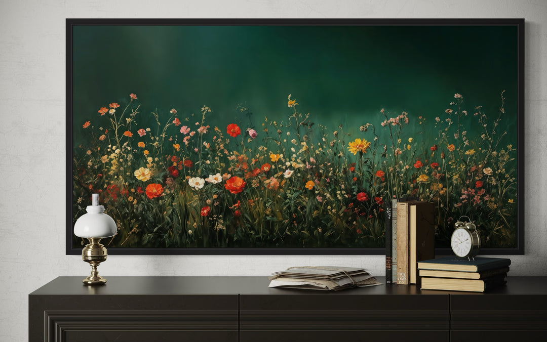 Framed canvas wall art of colorful wildflowers in a dark green field at night above a dark console.