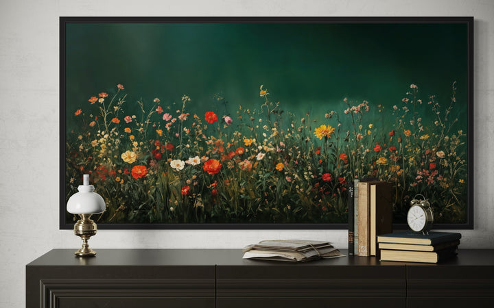 Framed canvas wall art of colorful wildflowers in a dark green field at night above a dark console.