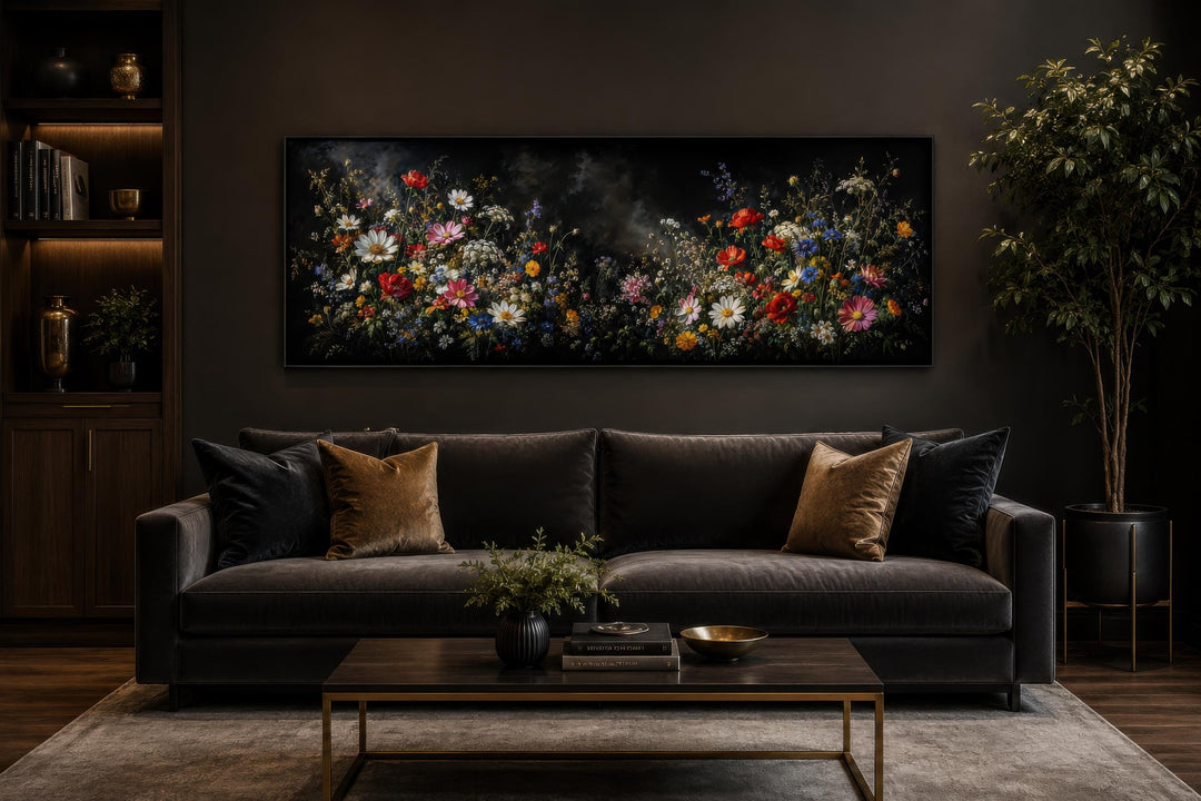 Long narrow canvas print of colorful wildflowers against a dark, moody background above a sofa.