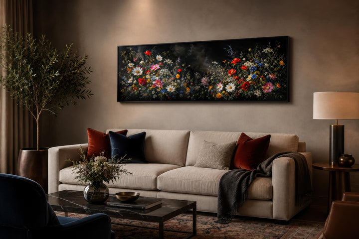 Long narrow dark moody wildflower canvas print hanging above a sofa in a modern living room.