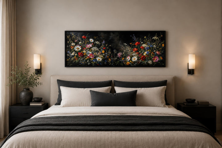 Long narrow canvas print of colorful wildflowers on a dark background above a modern bed.