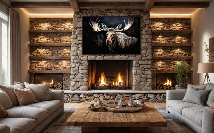 Framed moose canvas wall art hanging above a stone fireplace in a rustic cabin living room.
