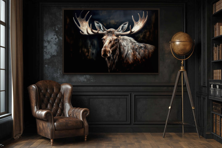 Framed canvas wall art of a moose against a dark background in a rustic study with a leather chair.