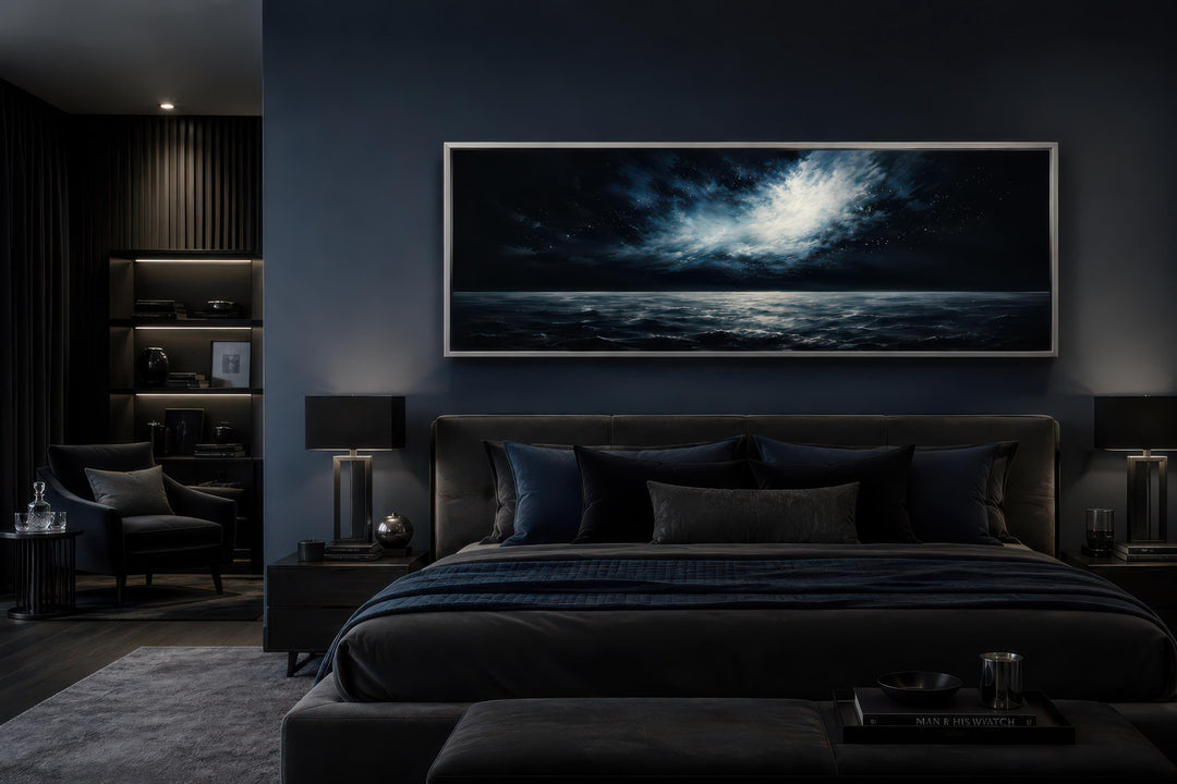 Wide horizontal canvas painting of a moonlit ocean storm above a bed in a dark navy bedroom.