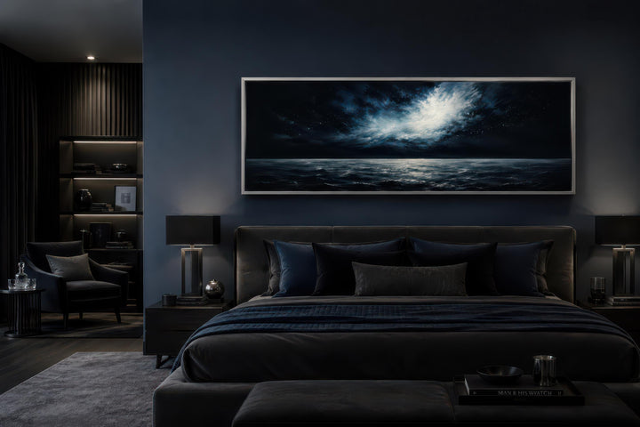 Wide horizontal canvas painting of a moonlit ocean storm above a bed in a dark navy bedroom.