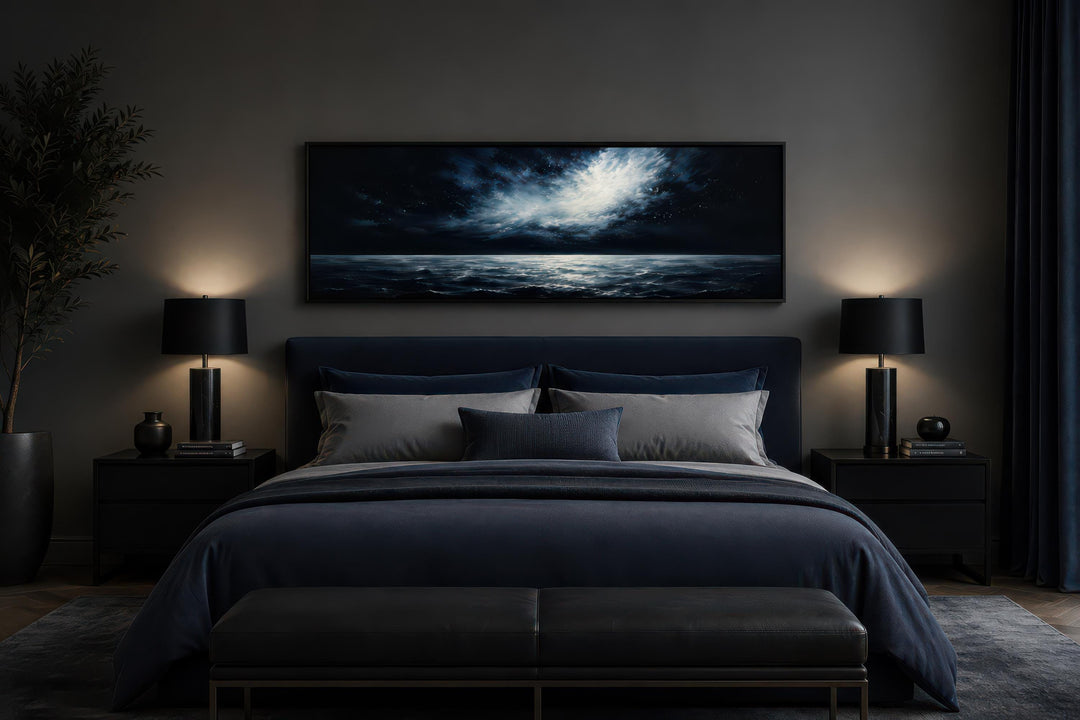 Dark navy moonlit ocean seascape painting hanging above a bed in a moody, modern bedroom.