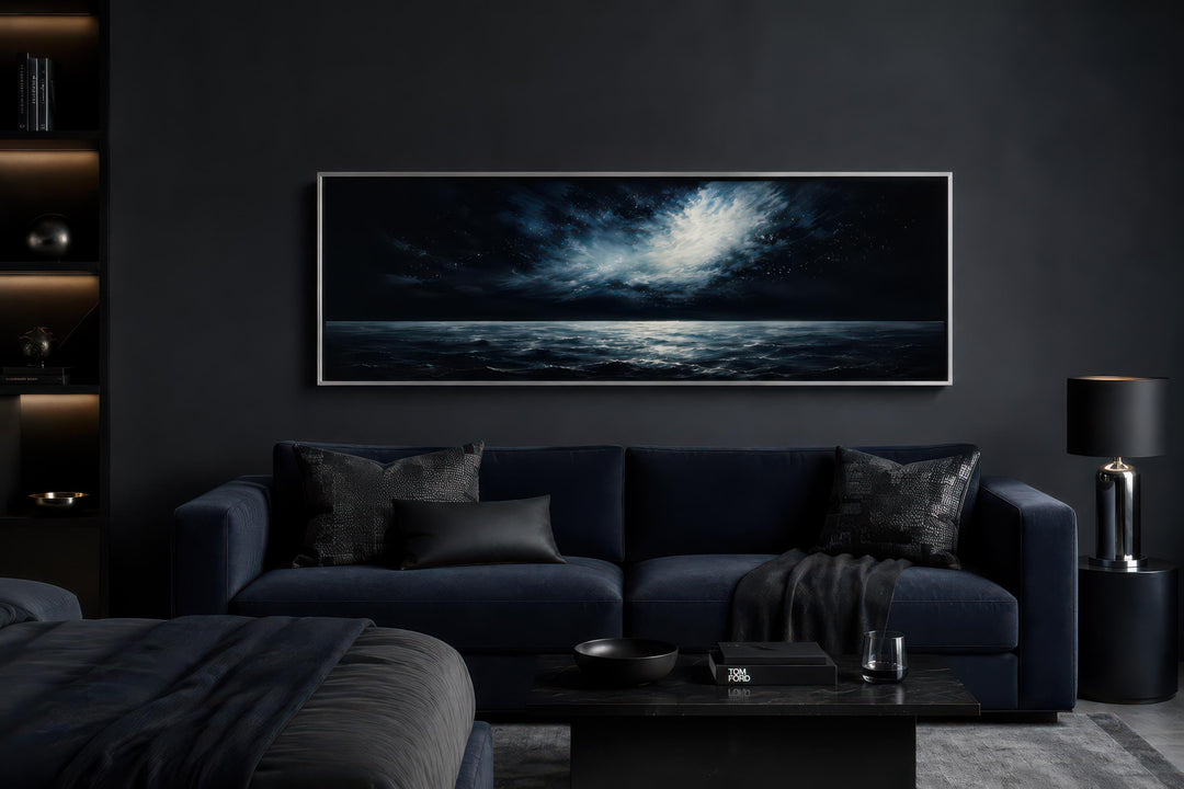 Wide horizontal canvas painting of a moonlit ocean and stormy night sky above a dark navy sofa.