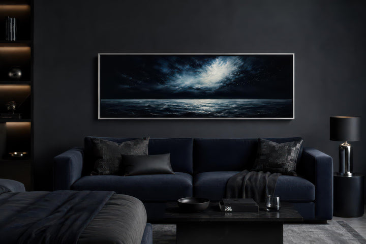 Wide horizontal canvas painting of a moonlit ocean and stormy night sky above a dark navy sofa.