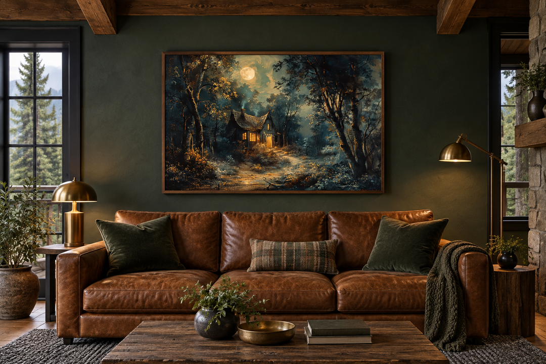 Framed wall art of a haunted cabin in a dark forest under a full moon above a brown leather sofa.