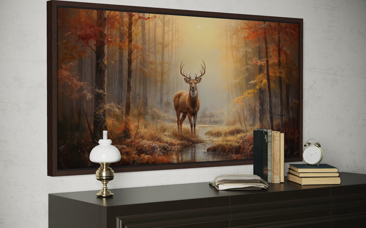 Large framed canvas print of a majestic stag in a golden autumn forest above a dark wood dresser.