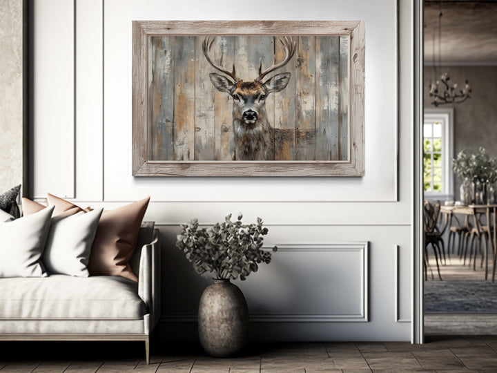 Deer painting in a rustic barnwood frame canvas wall art hanging above a sofa in a living room.
