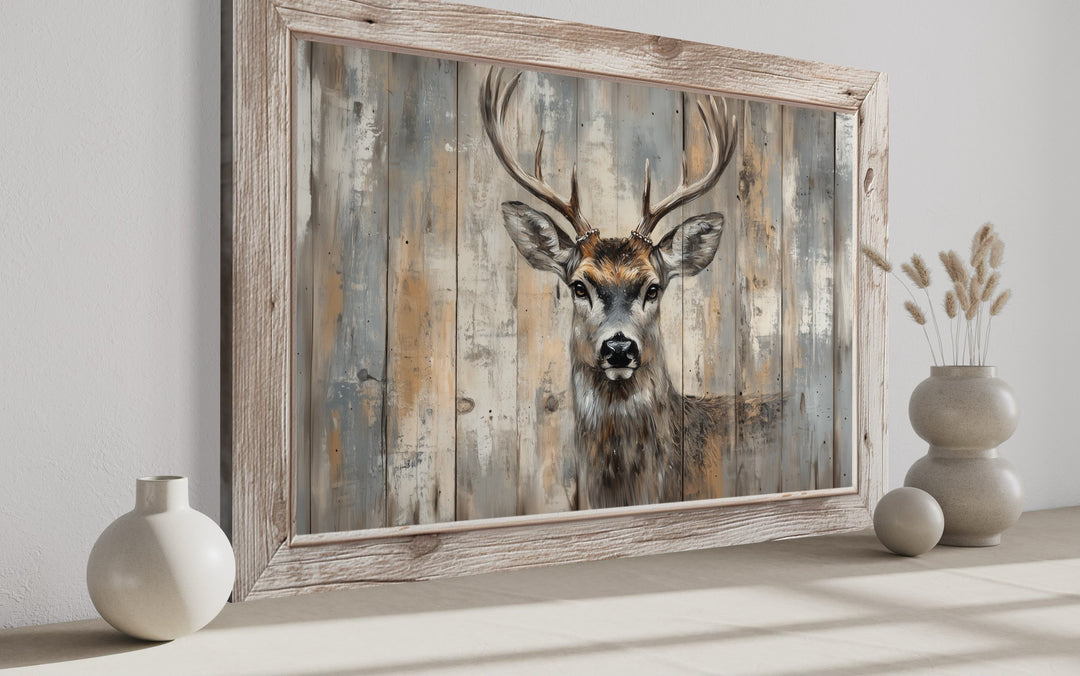 Deer painting on a rustic barnwood-style background in a light wood frame on a neutral surface.