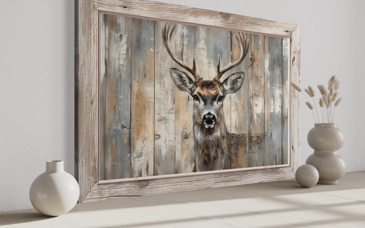 Deer painting on a rustic barnwood-style background in a light wood frame on a neutral surface.