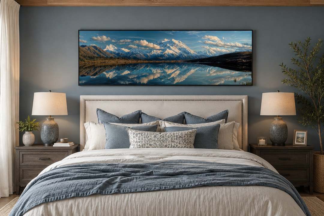 Panoramic wall art of Denali and Wonder Lake reflecting snowy peaks above a bed in a blue bedroom.