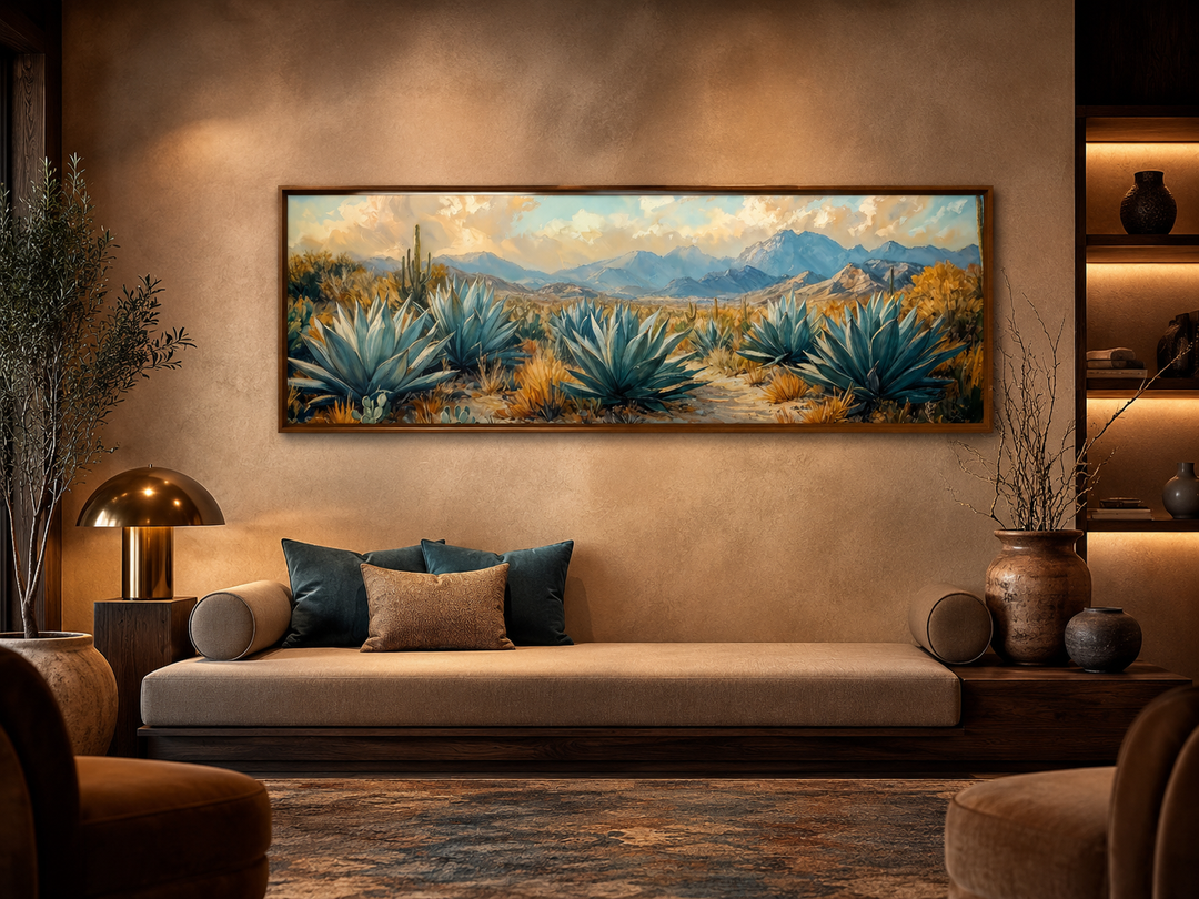 Long horizontal wall art of blue agave plants in a desert landscape above a modern sofa.