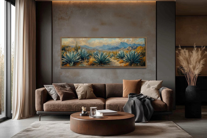 Panoramic desert agave painting in a modern living room above a brown sofa.