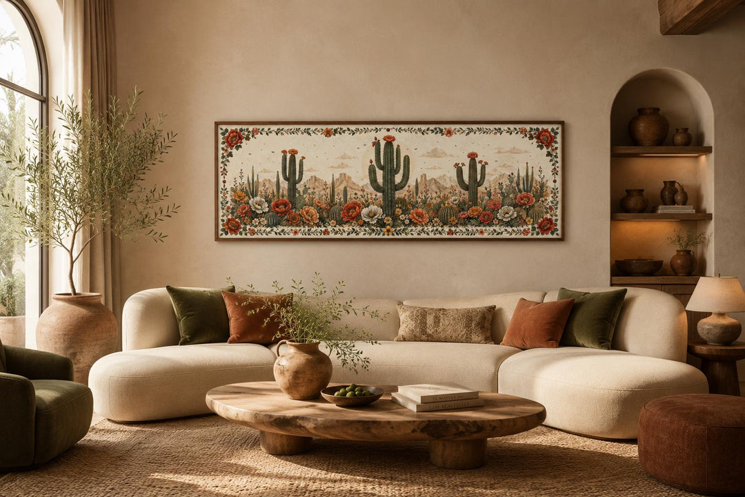 Long narrow canvas wall art of blooming saguaro cacti in a desert landscape above a curved sofa.