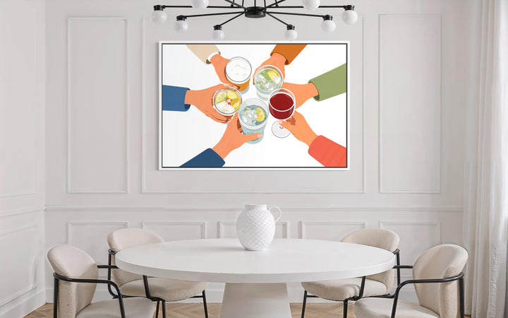 A modern canvas print of friends toasting drinks hangs above a white dining table and chairs.