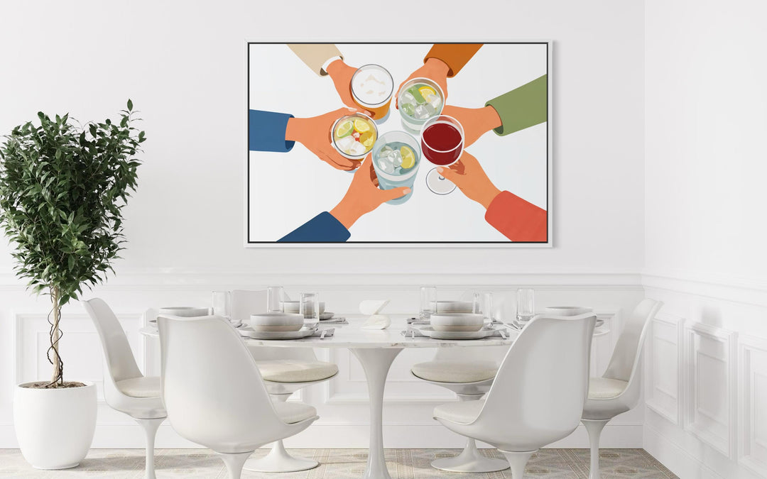 A modern canvas print of friends toasting drinks hangs above a white dining table and chairs.