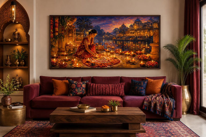 Diwali canvas wall art of a woman lighting diyas above a burgundy sofa in a warm living room.
