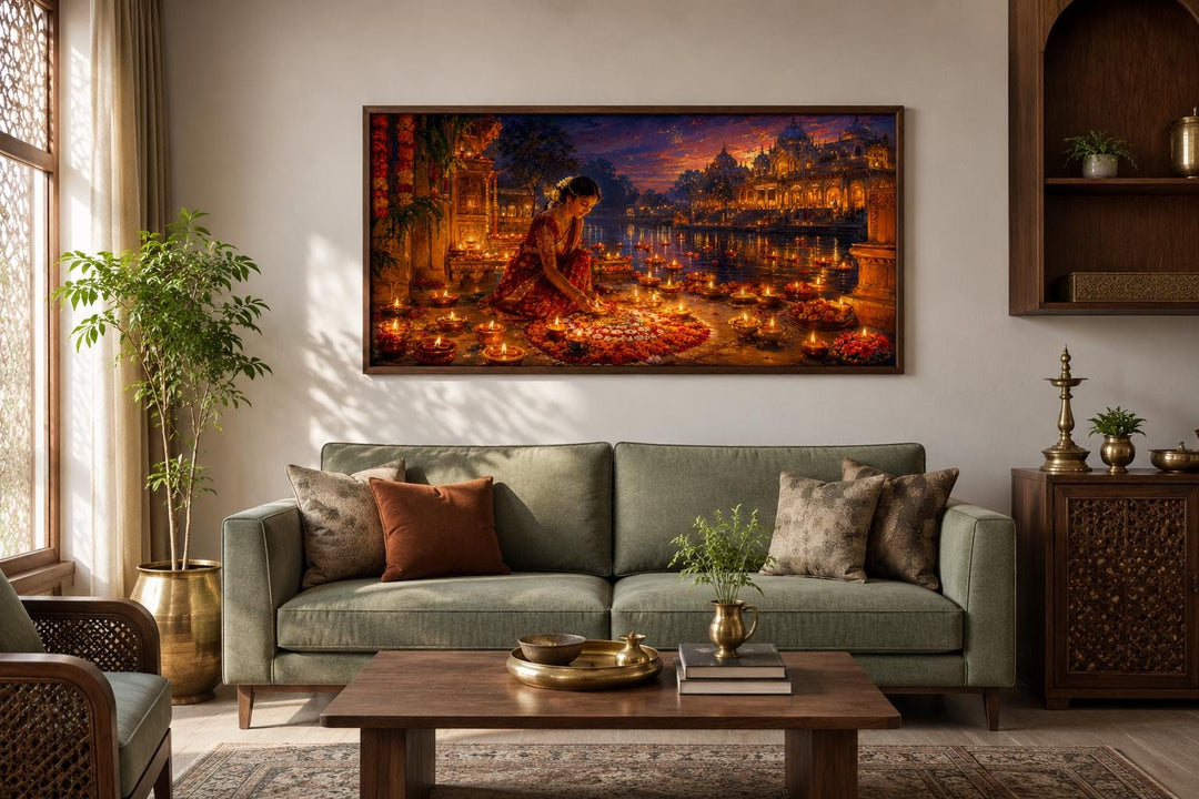 Diwali canvas wall art of a woman lighting diyas, hung above a green sofa in a living room.
