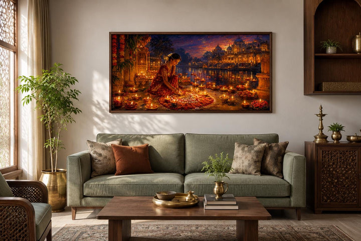 Diwali canvas wall art of a woman lighting diyas, hung above a green sofa in a living room.