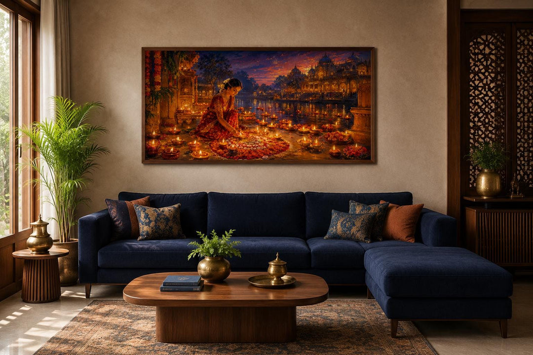 Diwali canvas wall art of a woman lighting diyas, hung above a blue sofa in a living room.