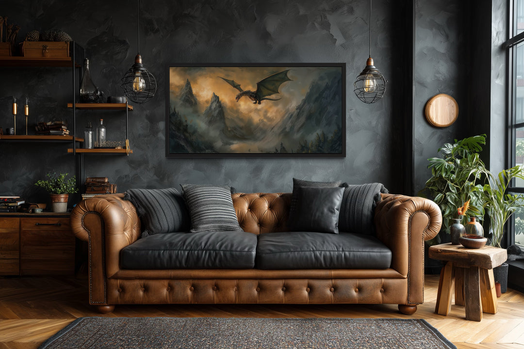 Framed panoramic canvas art of a dragon flying over misty mountains above a brown leather sofa.