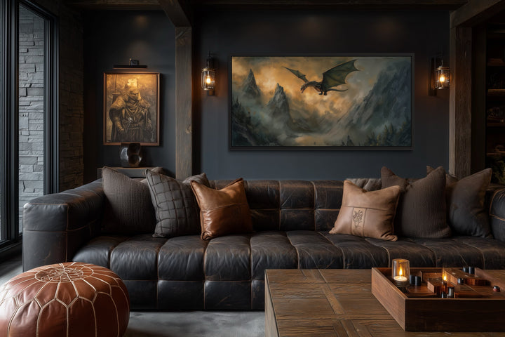 Framed panoramic canvas art of a dragon flying over misty mountains above a dark leather sofa.