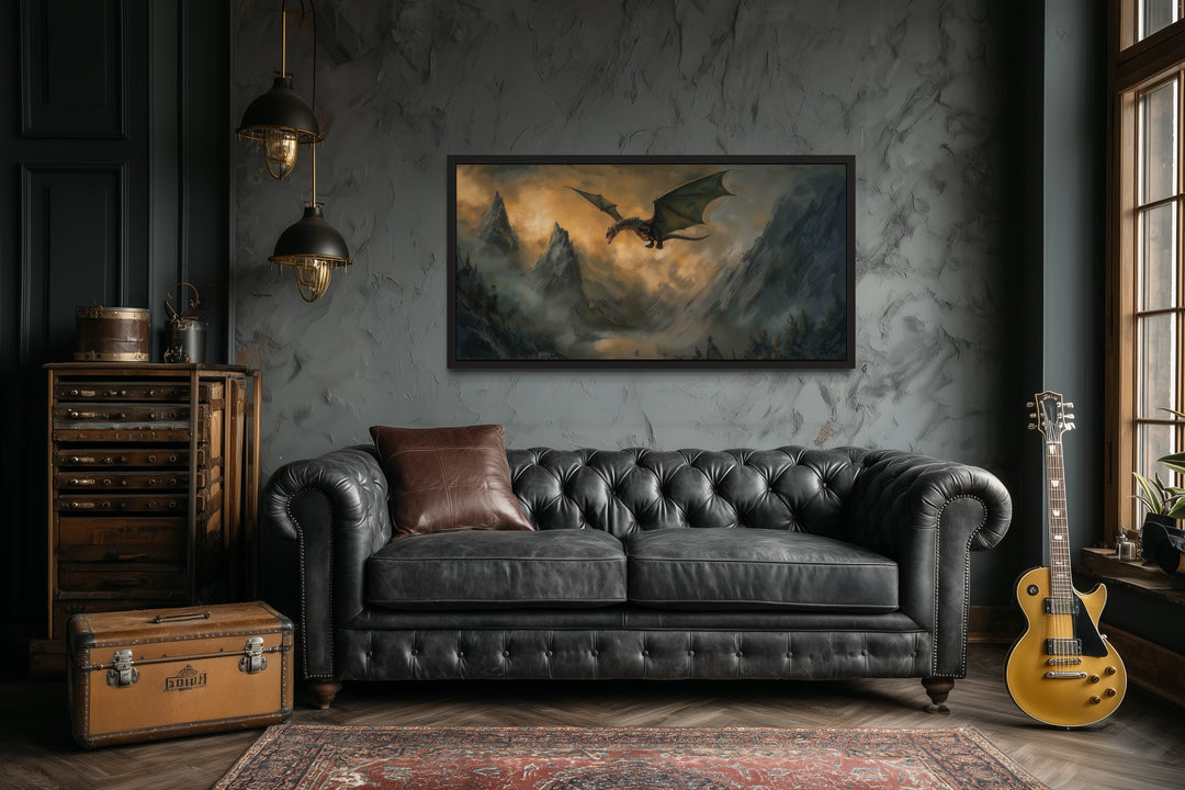 Framed panoramic canvas art of a dragon flying over mountains above a black leather sofa.