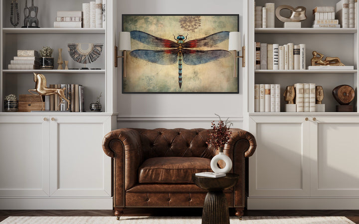 Dragonfly Vintage Rustic Framed Canvas Wall Art above a brown leather chair in a library setting.