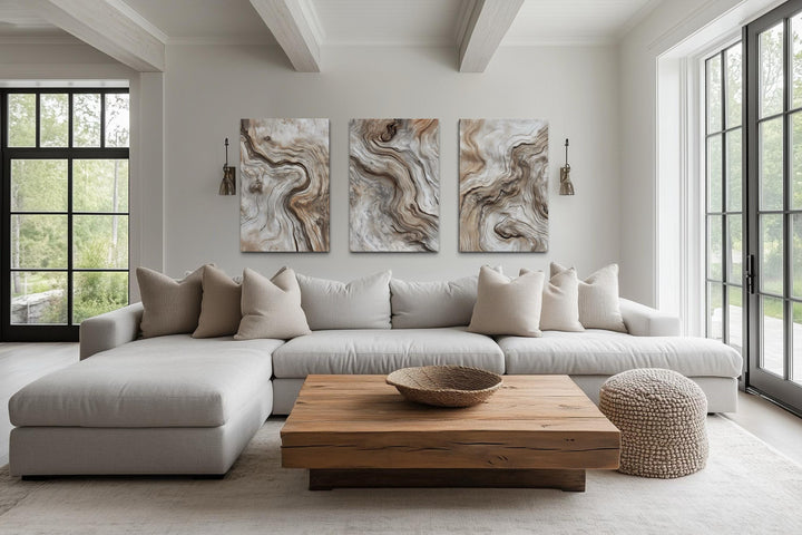 A triptych of vertical canvas wall art featuring abstract driftwood grain patterns above a sofa.
