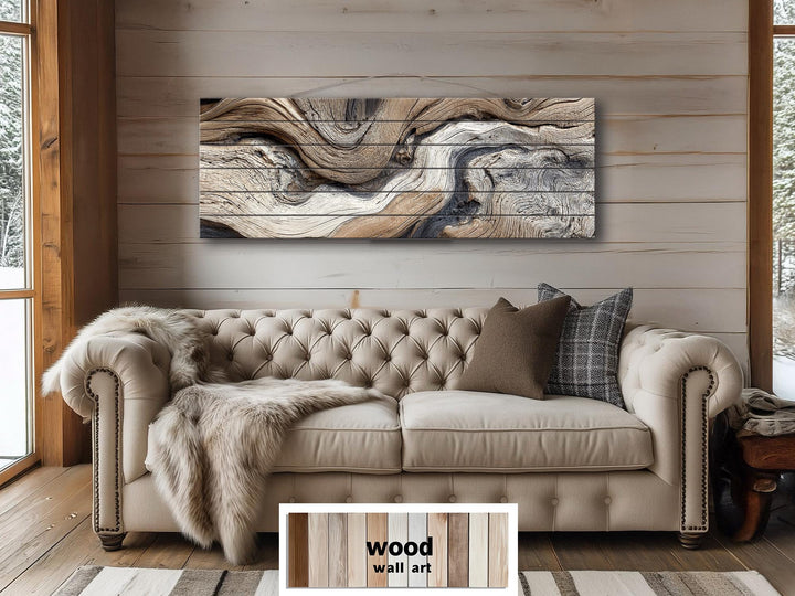 Large horizontal driftwood painting on wooden planks displayed above a tufted beige sofa.
