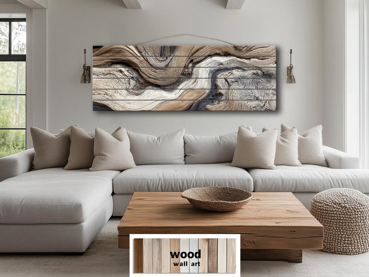 Large horizontal driftwood painting on wood planks above a neutral sofa in a modern living room.