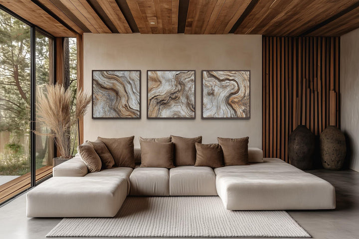 Triptych of driftwood wood grain canvas wall art in a modern coastal living room.